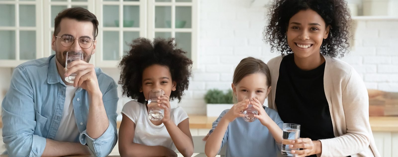 A happy family drinking glasses of water in their kitchen
